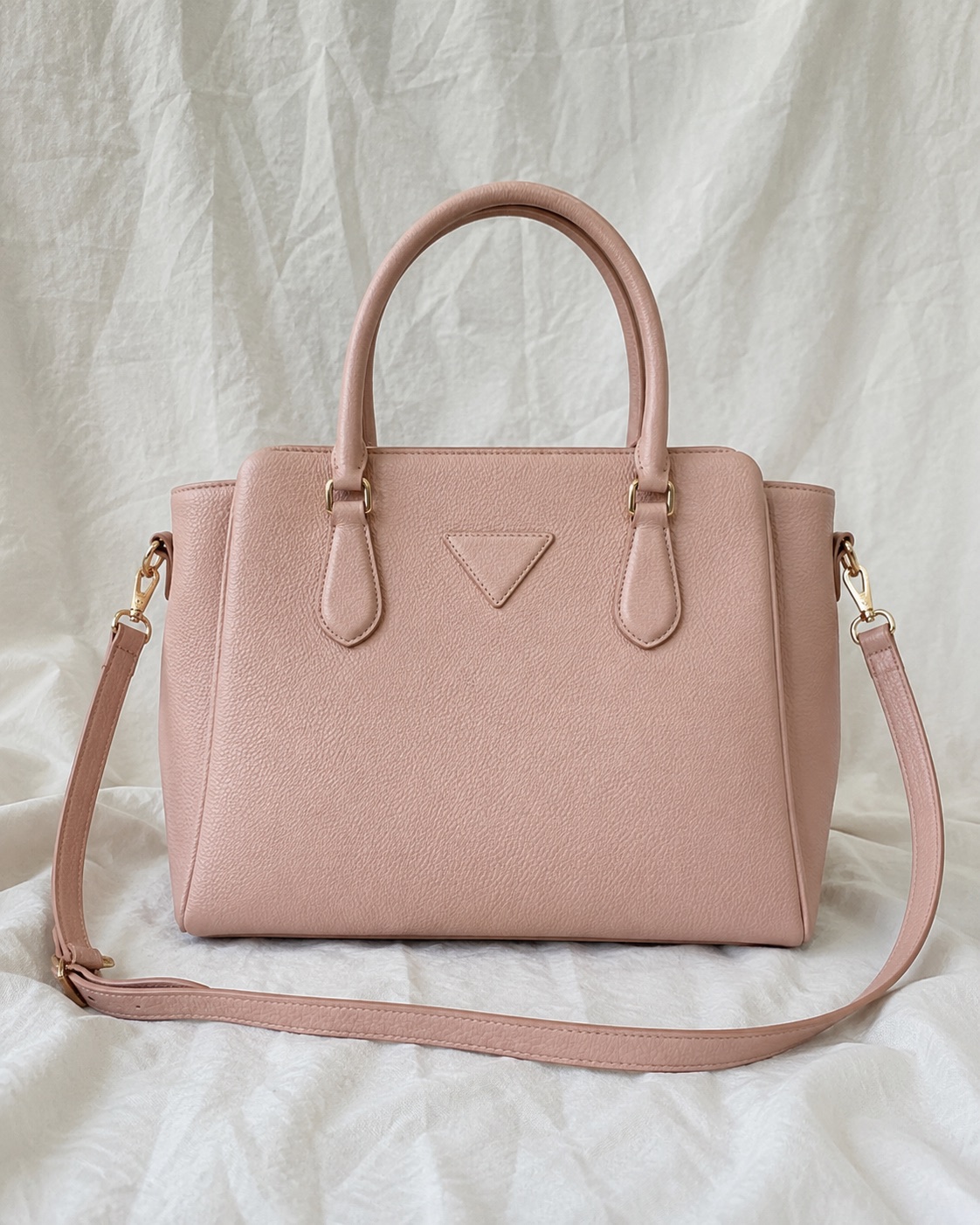 Pink handbag on a wrinkled fabric backdrop before background removal